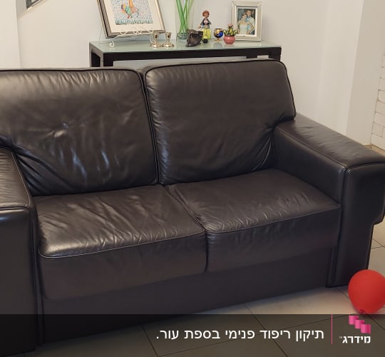 ספת עור זוגית כהה מרופדת בסלון ביתי